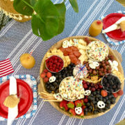 4th of July charcuterie board with plant, blue tablecloth and flag.