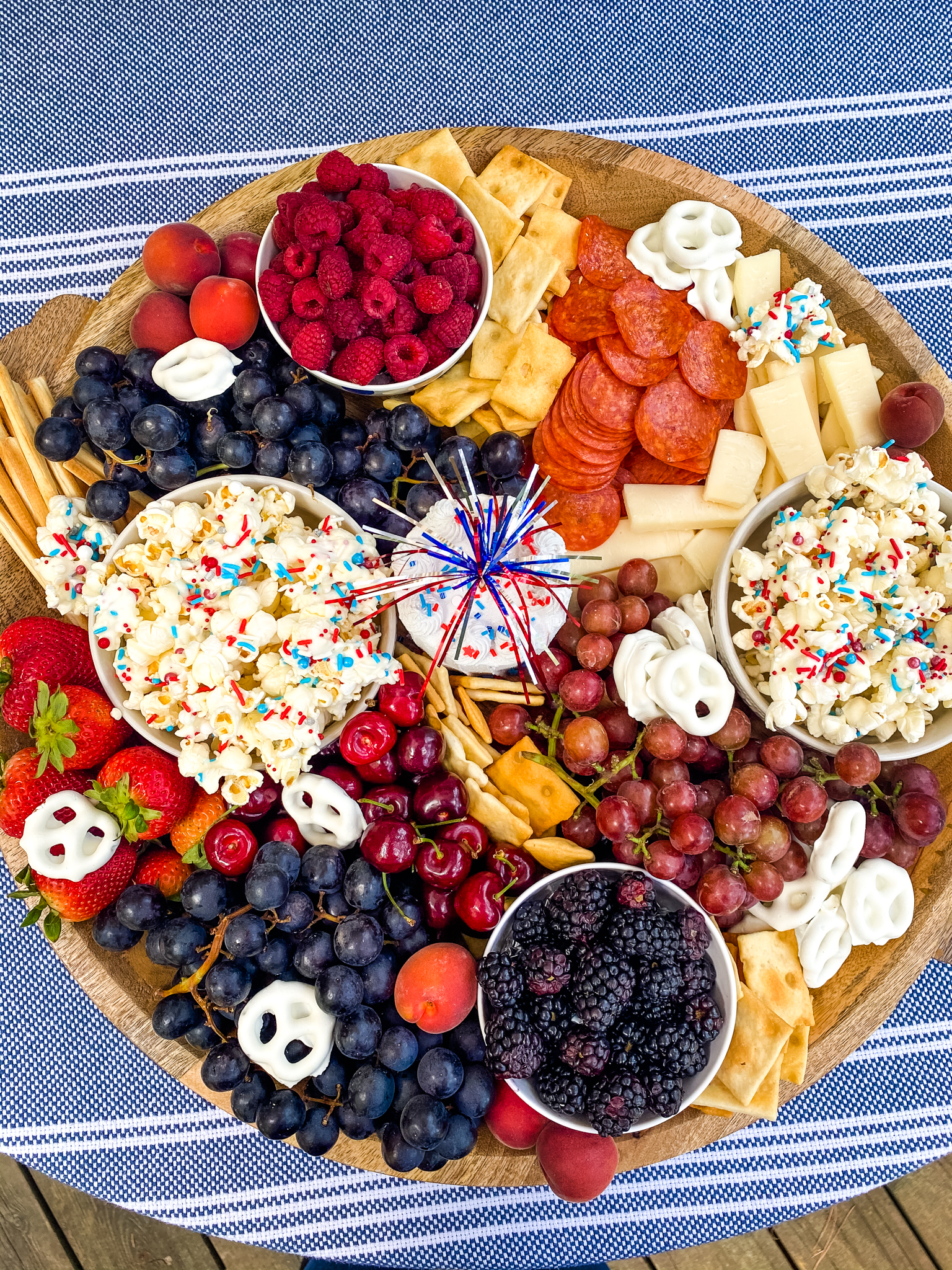 Red, white and blue charcuterie board with blue tablecloth.
