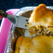 Metal spatula lifting up chicken casserole topped with pillsbury crescent rolls.