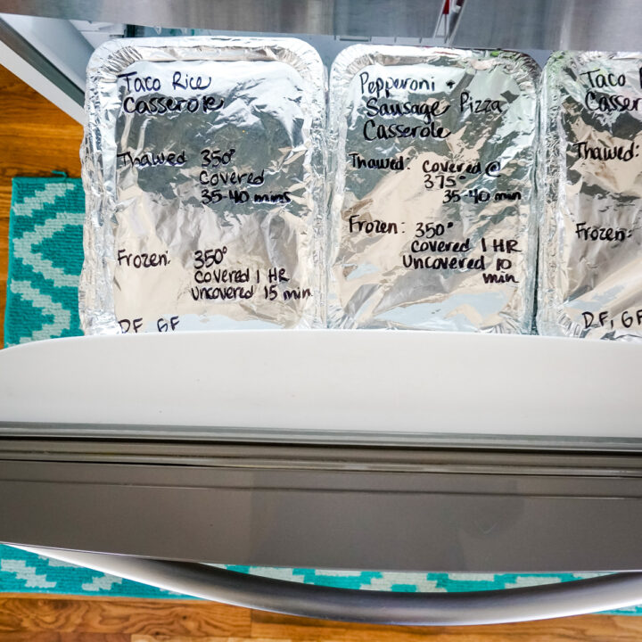Bottom freezer open with casseroles wrapped in tin foil and labeled with sharpie advertising freezer casserole recipes.