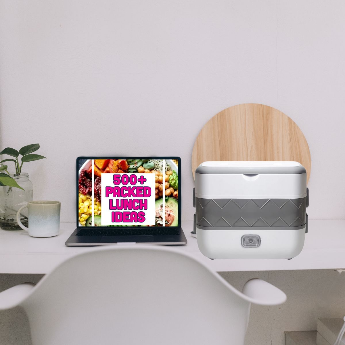 Computer, mug, plant and electric lunch box on white desk with white chair. Computer screen has a 500+ packed lunch ideas image on the screen.