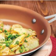 Copper colored gotham steel pan with fried potatoes and parsley inside