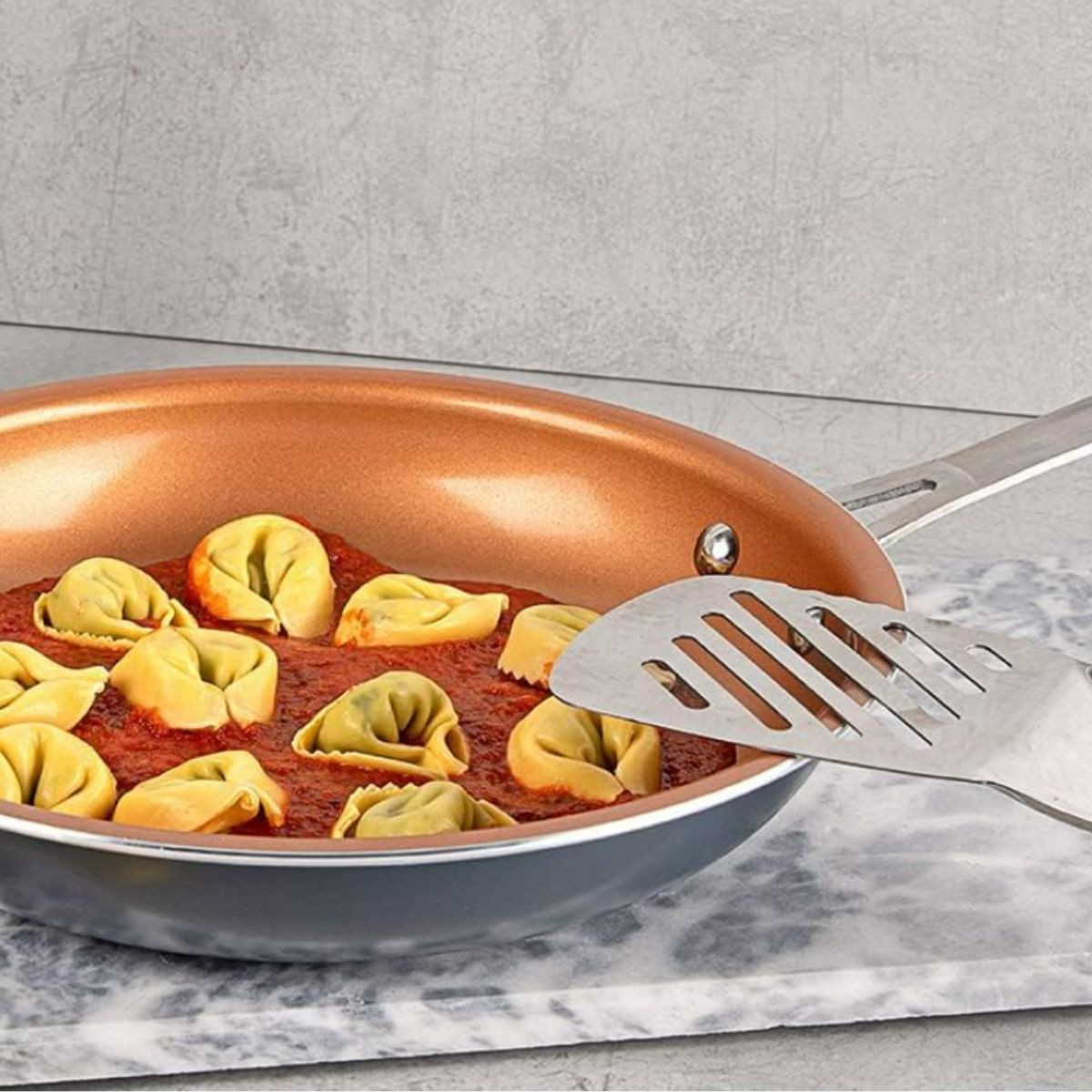 copper colored gotham steel frying pan with tortellini inside and red sauce