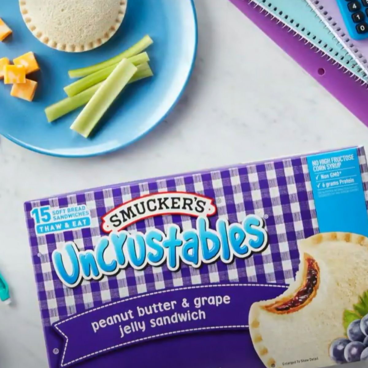 Box of grape uncrustables next to a plate of celery