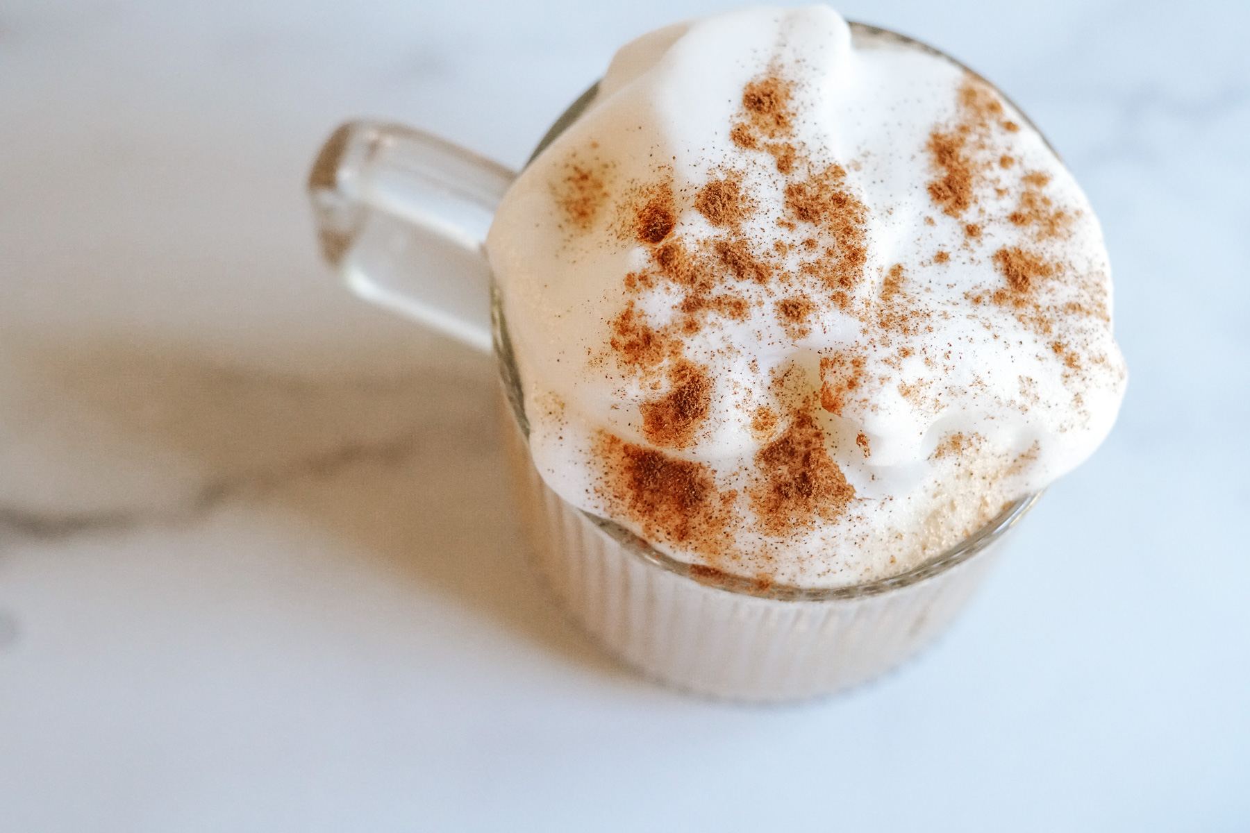 Coffee with Honey topped with Foam and Cinnamon in a Clear Glass
