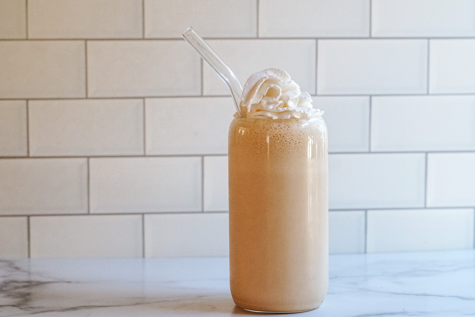 Copycat Chick-fil-A Frosted Coffee in a clear glass topped with whipped cream with a clear glass straw.