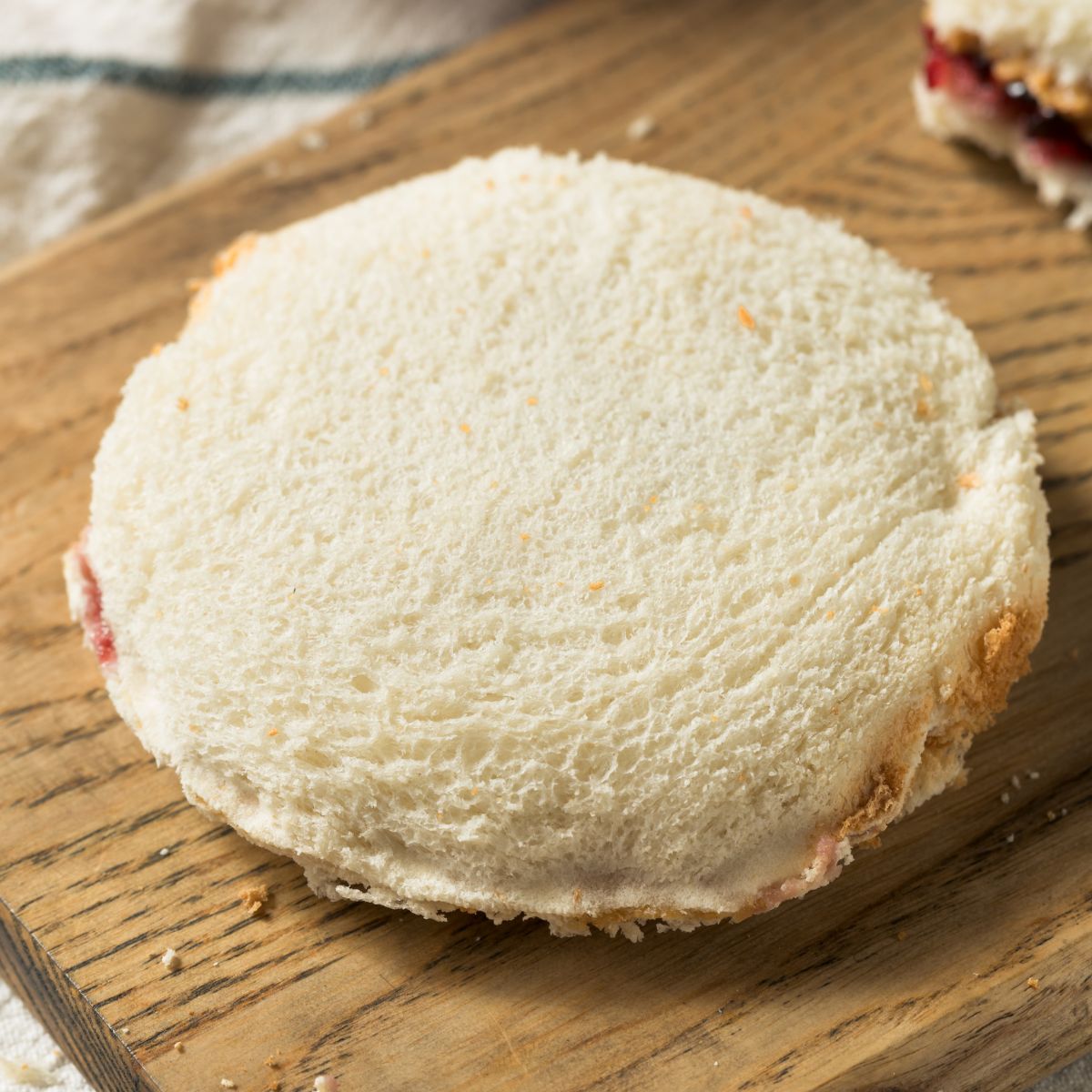 Sandiwch on a cutting board with all the crusts cut off. Sandwich is in the shape of a circle.