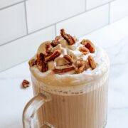 Starbucks Chestnut Praline Latte in a clear mug with whipped cream and pralines on top.
