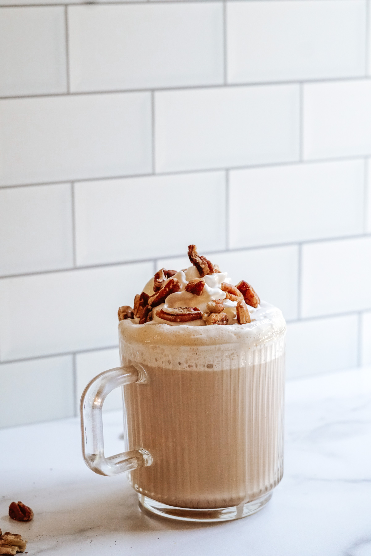 Starbucks Copycat Chestnut Praline Latte in a clear mug topped with whipped cream and chopped pralines.