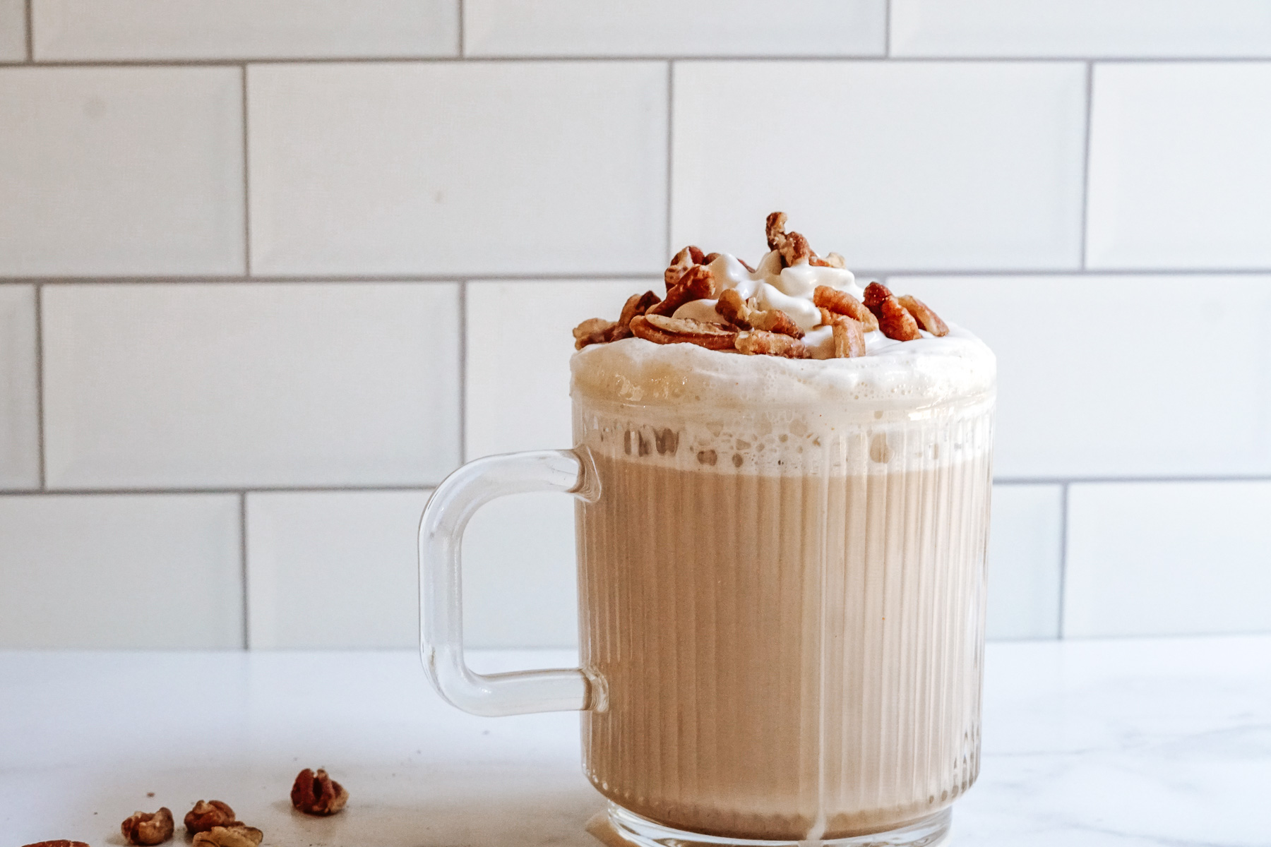 Starbucks Copycat Chestnut Praline Latte in a clear mug topped with whipped cream and chopped pralines.