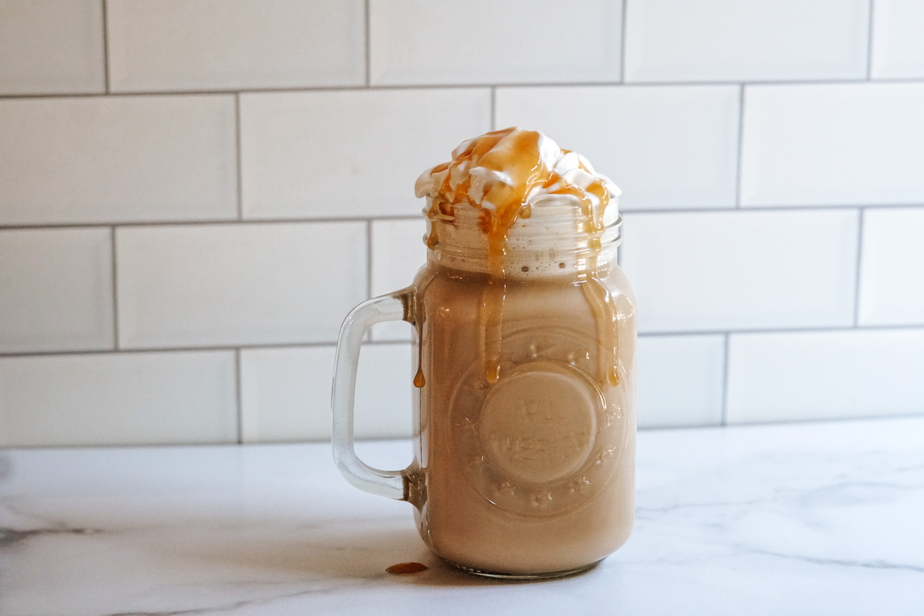 Copycat Starbucks Caramel Brulée Latte in a glass jar topped with whipped cream and caramel sauce.