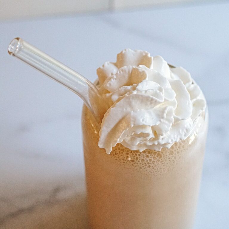 Chick Fil A Frosted Coffee in a glass jar with whipped cream on top and a glass straw.