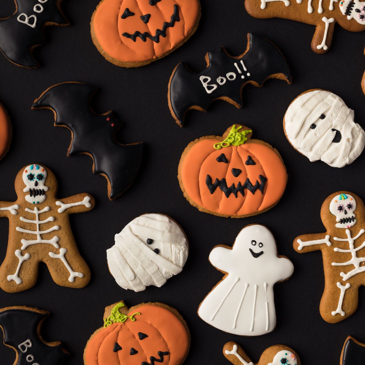 Halloween frosted cookies on black background. Ghosts, pumpkins, skeletons and bats