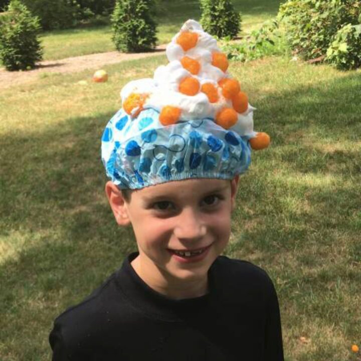Boy wearing shower cap covered in shaving cream and orange cheese puffs