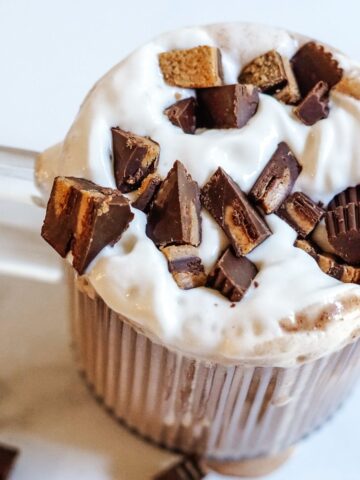 Sliced peanut butter cups on a mug of Bailey's hot chocolate and whipped cream