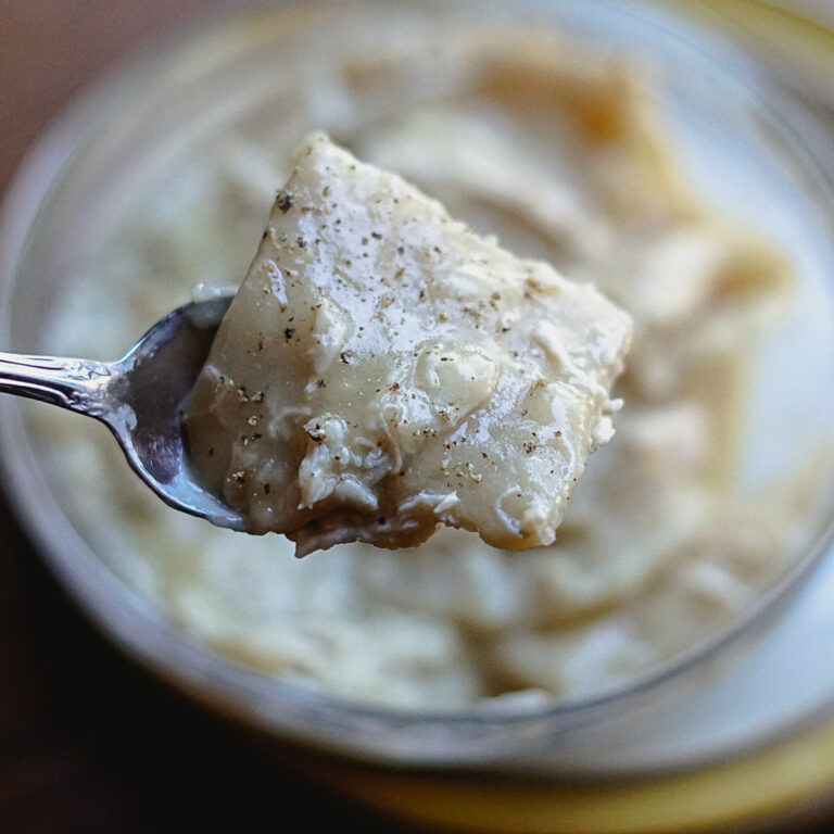 Dairy free chicken and dumplings in a glass bowl with a spoon, salt and pepper