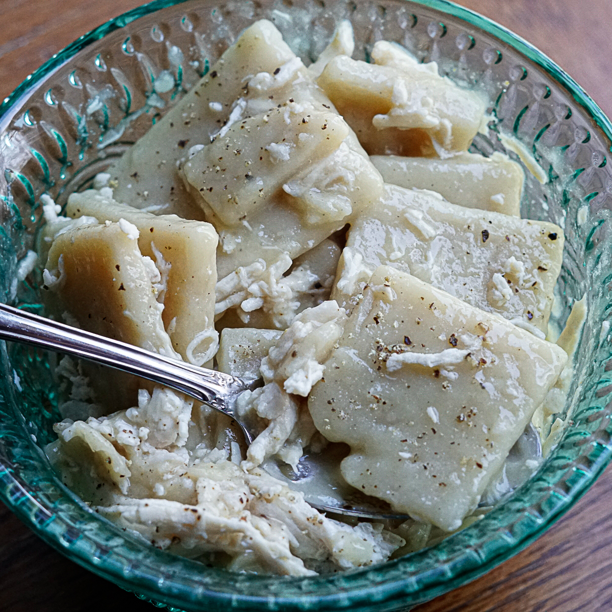 Gluten Free Cracker Barrel Copycat Recipe Chicken and Dumplings on a fork with salt and pepper in a teal bowl.