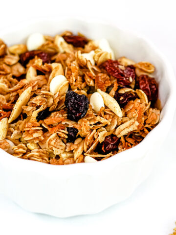 Close up of Gingerbread granola in a white bowl on a white countertop.