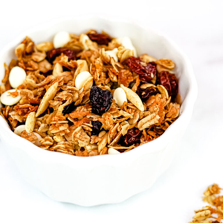 Close up of Gingerbread granola in a white bowl on a white countertop.