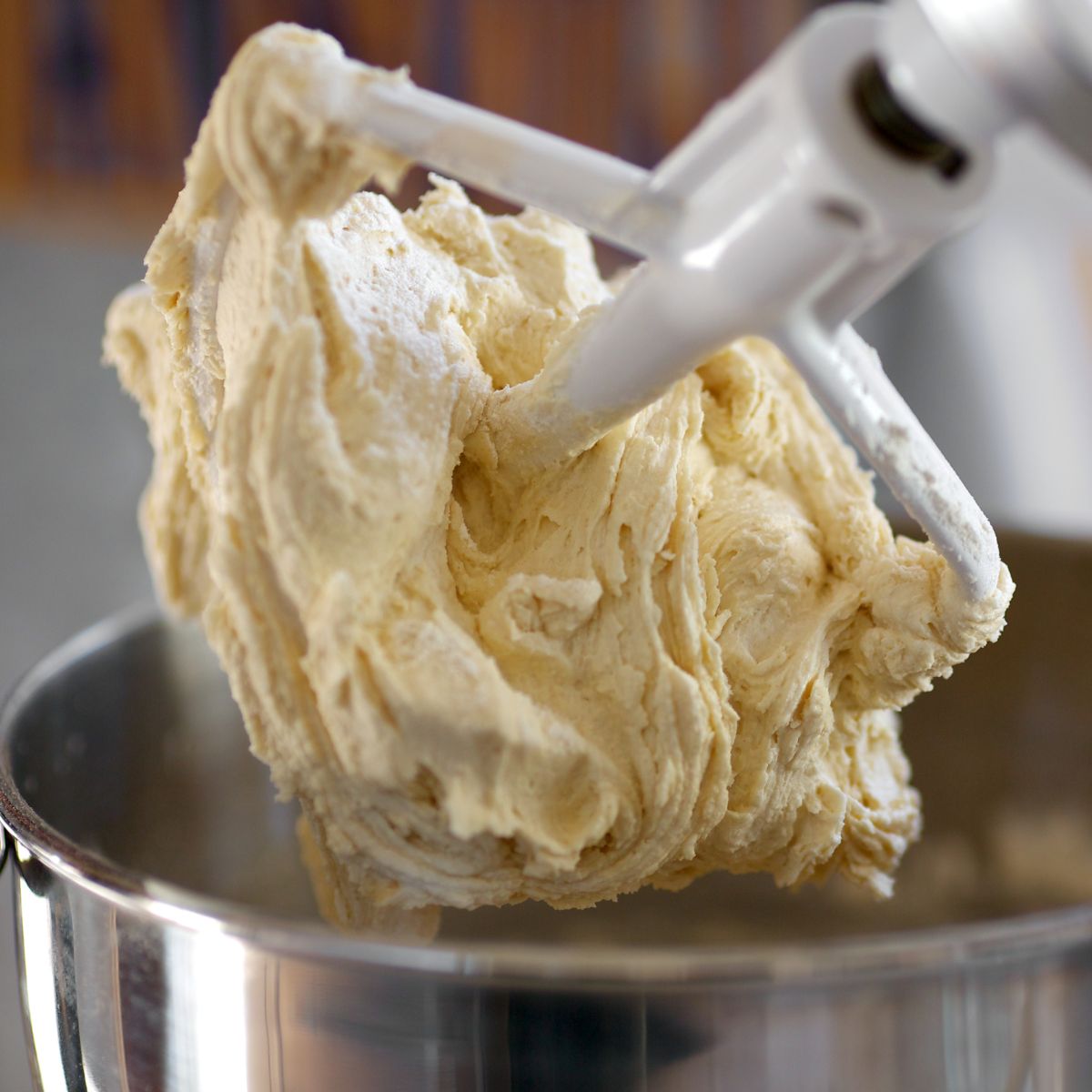 Stand mixer with the paddle lifted showing the process of whipping cinnamon honey butter.