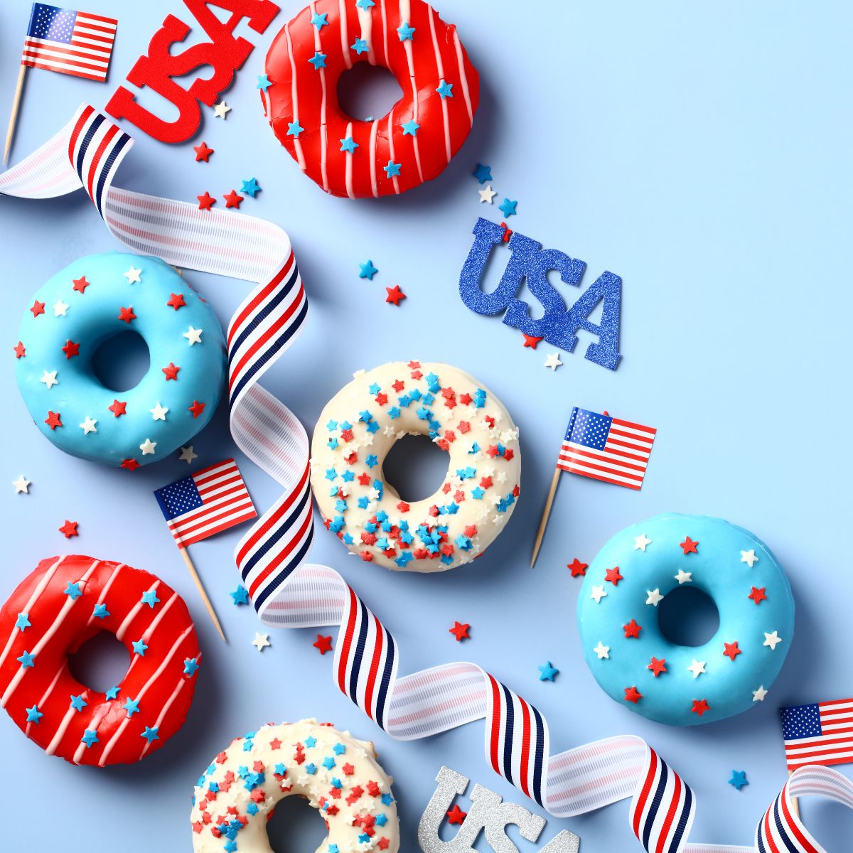 Red white and blue donuts, confettie and flags on pale blue background