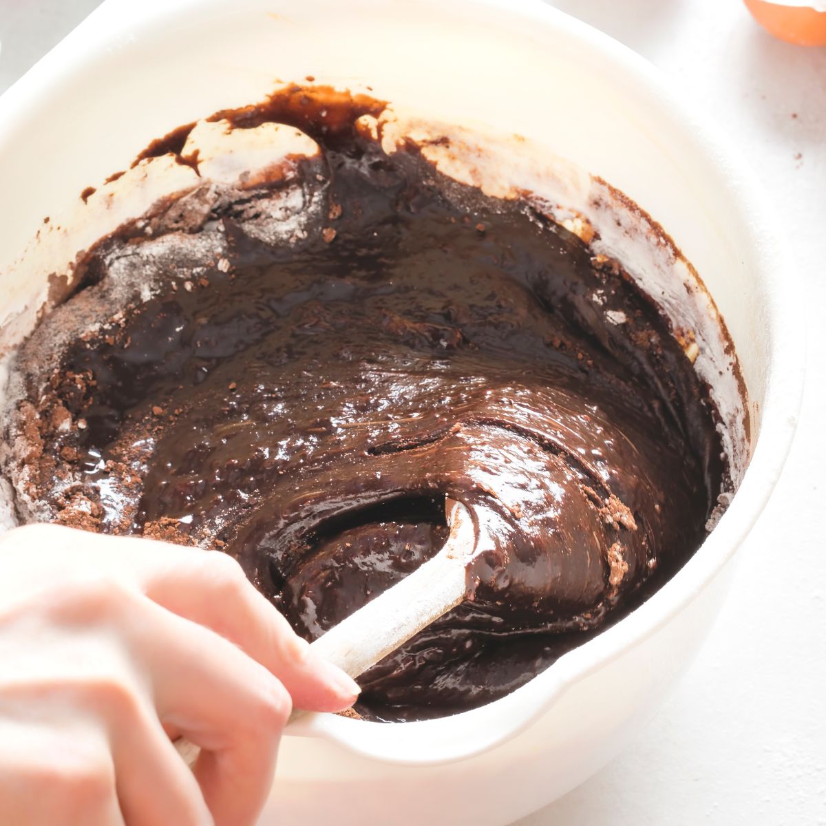 Brownie batter in white bowl with wooden spoon