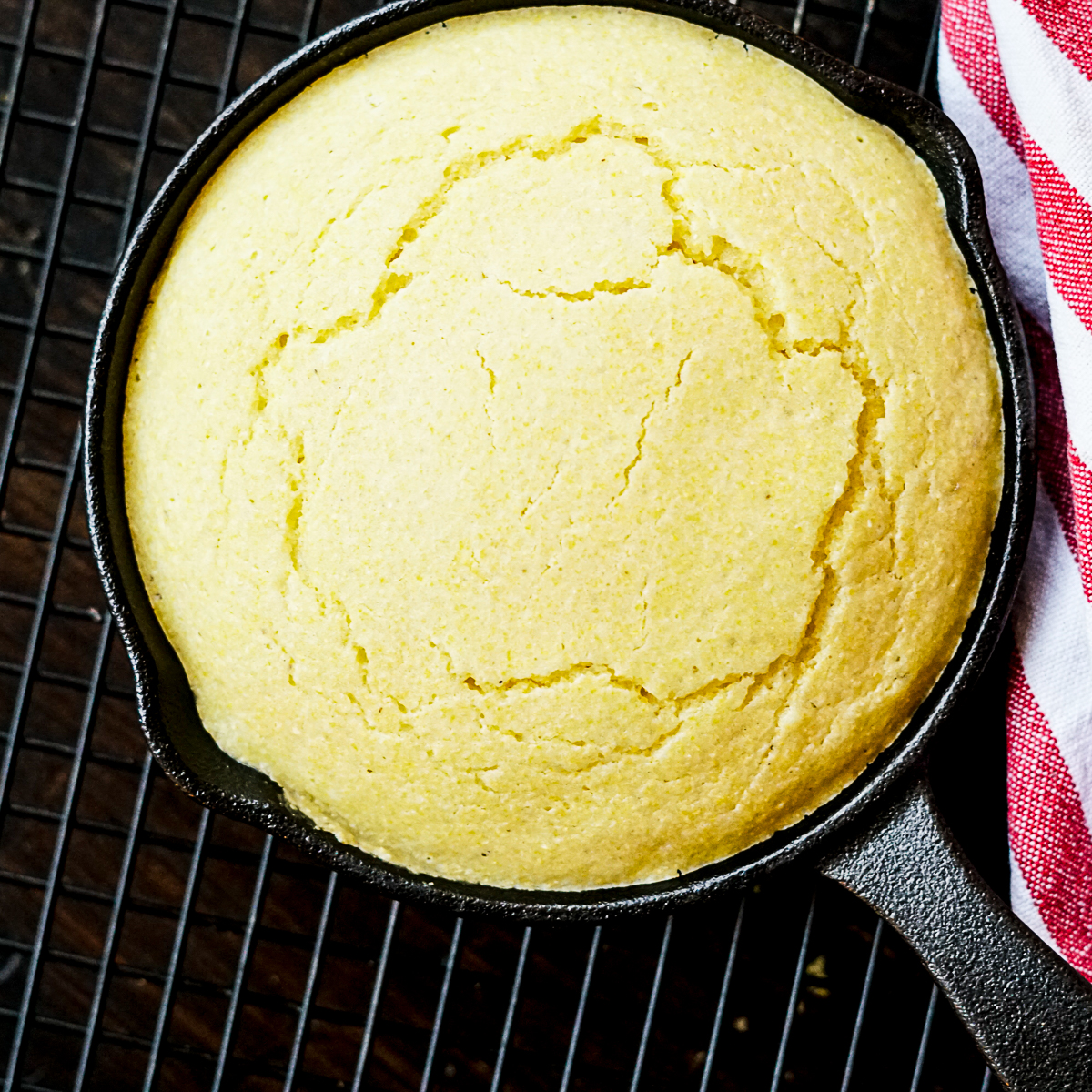 Dairy Free Cracker Barrel Cornbread Muffins Copycat Recipe in a cast iron skillet on a wire rack with a red and white striped towel