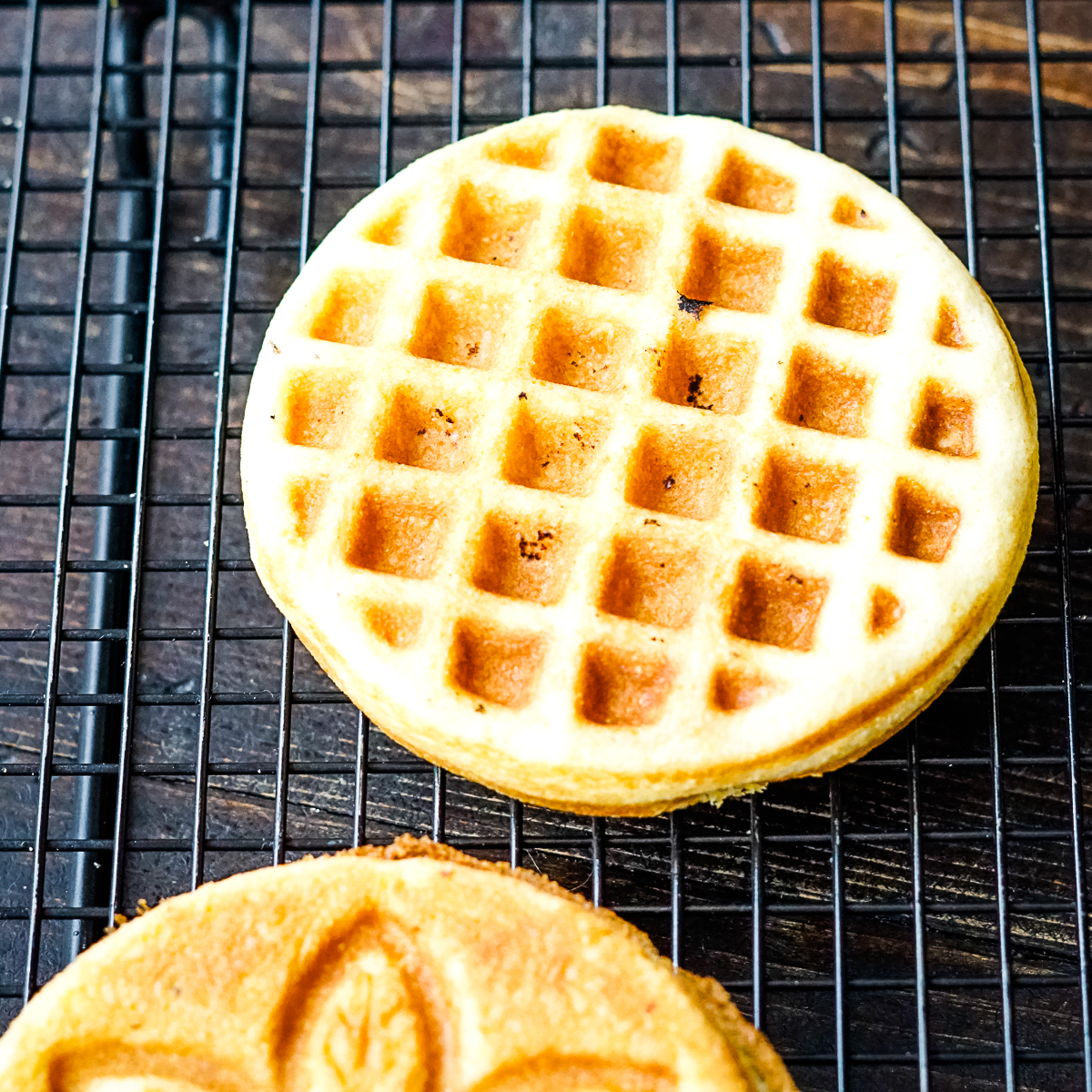 Two cornbread waffles on a metal cooling rack
