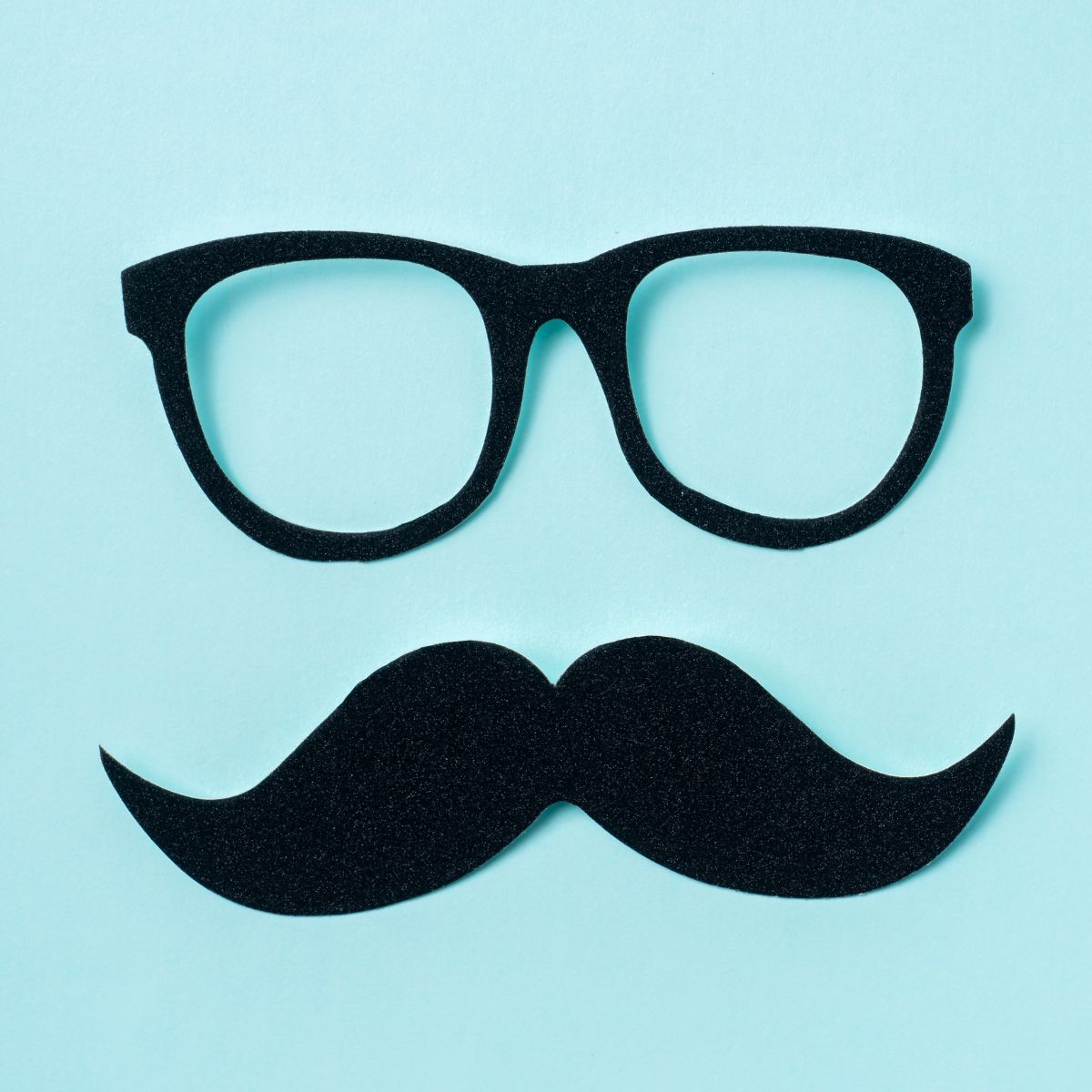 Black paper glasses and black paper mustache on blue background