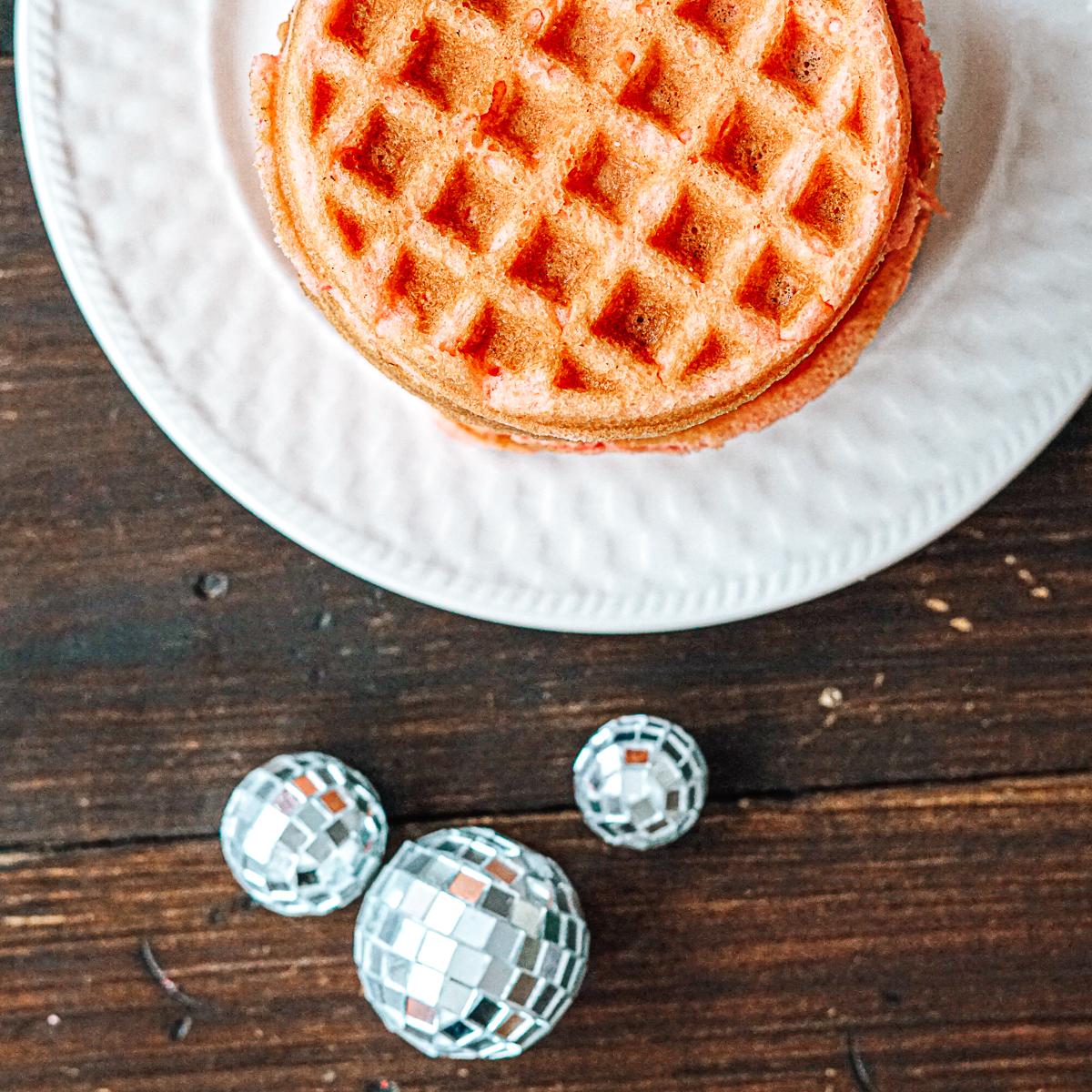 Stack of Strawberry Cake Waffles on a white plate with three disco balls
