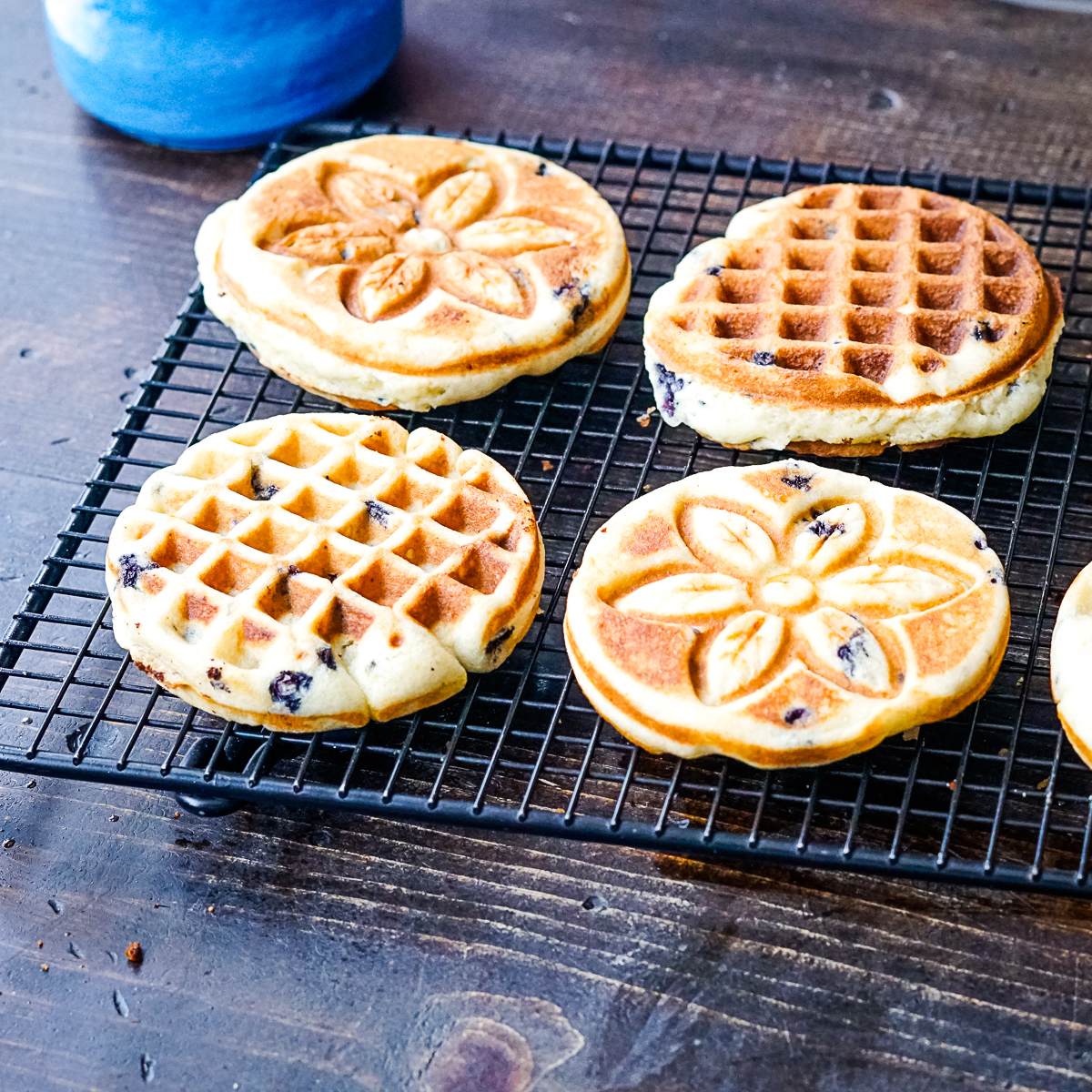 Four blueberry muffin waffles on a cooling rack