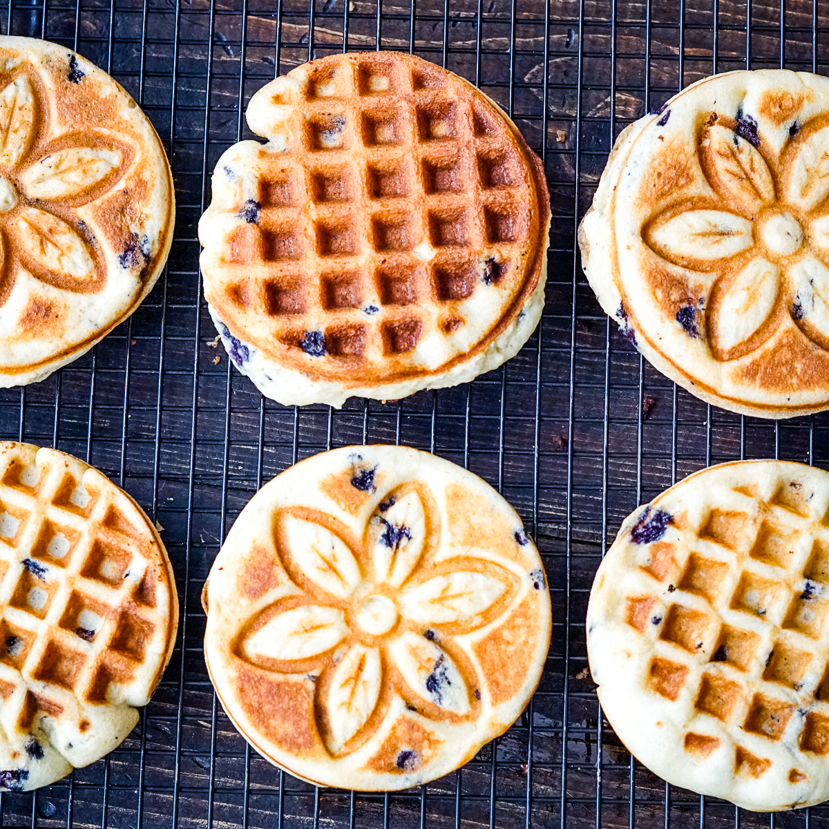 Six blueberry muffin waffles on a cooling rack